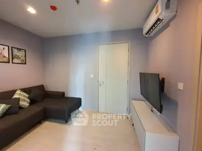 Modern living room with sleek sofa, wall-mounted TV, and air conditioning unit.
