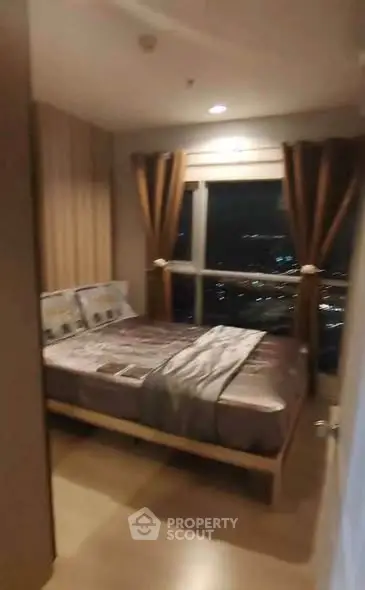 Cozy bedroom with city view, featuring a comfortable bed and elegant curtains.