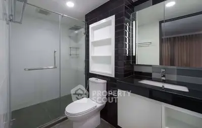 Modern bathroom with sleek black tiles and glass shower enclosure