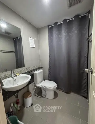 Modern bathroom with sleek fixtures and elegant gray shower curtain.