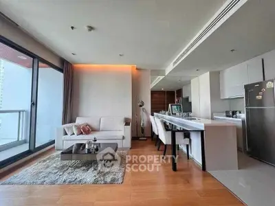 Modern open-layout living room with kitchen, featuring sleek furniture and large windows for natural light.