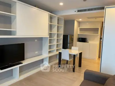 Modern living room with built-in shelves and compact dining area in a stylish apartment.