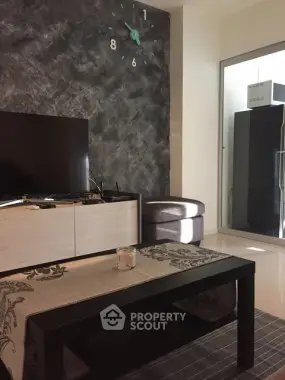 Modern living room with stylish decor and wall clock, featuring a sleek TV setup and elegant furniture.