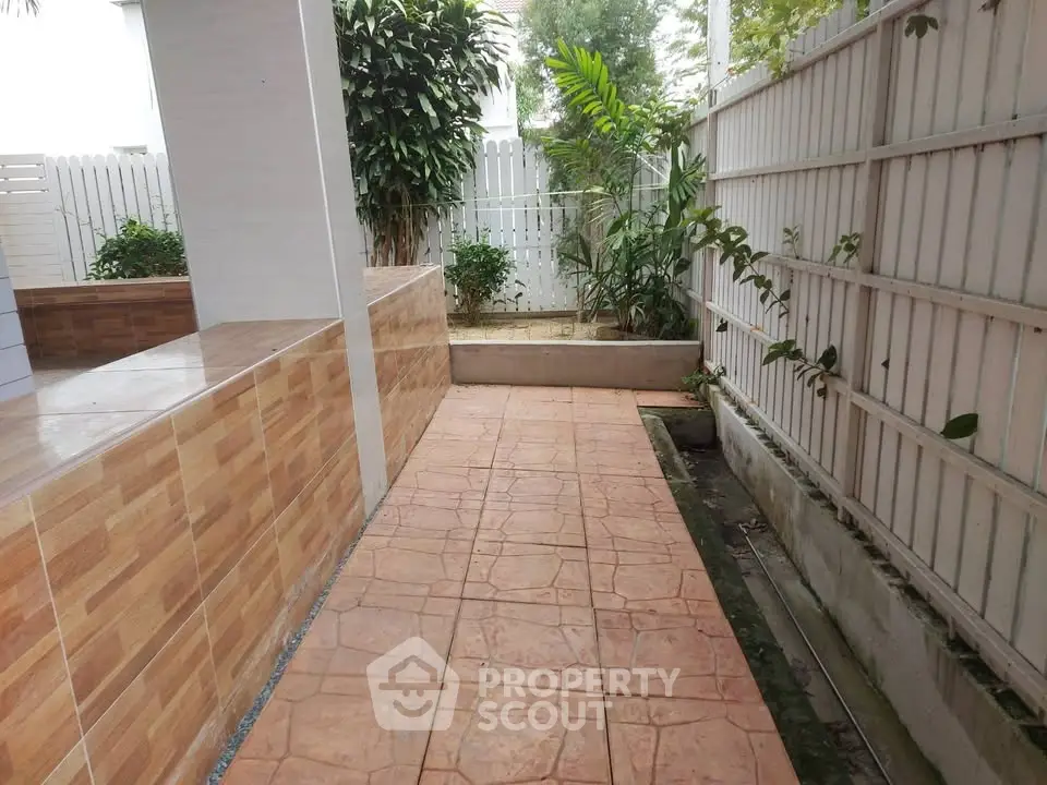 Charming garden pathway with tiled flooring and lush greenery, perfect for serene outdoor living.