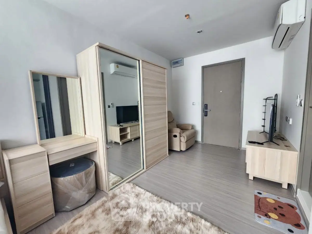 Modern living room with sleek furniture and mirrored wardrobe in a cozy apartment.