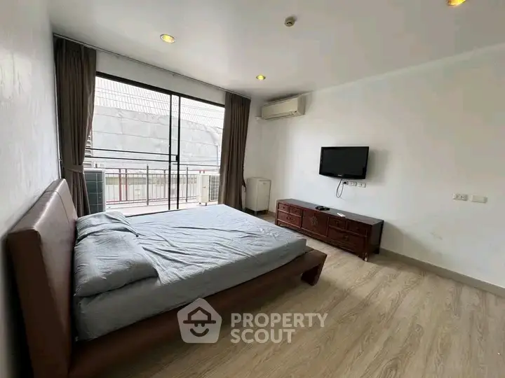 Spacious bedroom with modern furnishings and balcony access in a stylish apartment.