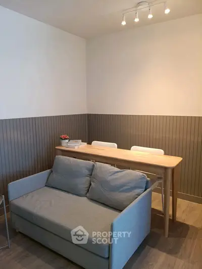 Cozy living room with modern sofa and dining table, perfect for small apartments.