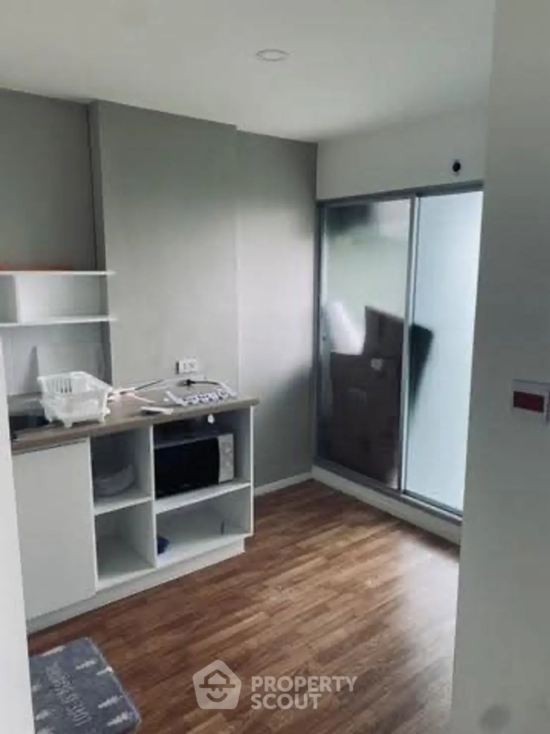 Modern kitchen with sleek design and wooden flooring, featuring built-in shelves and large frosted glass window.