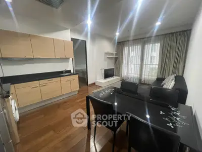 Modern open-plan kitchen and living area with sleek wooden flooring and stylish furnishings.