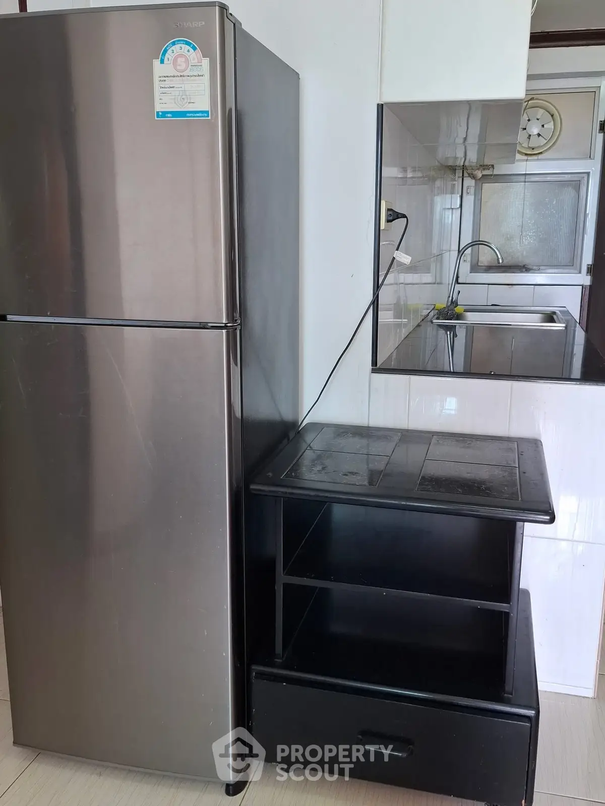 Modern kitchen with stainless steel fridge and sleek black shelving unit.