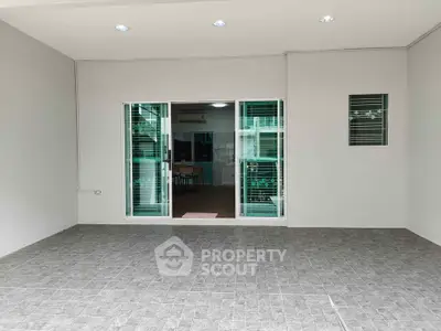 Spacious tiled patio with sliding glass doors leading to modern interior, perfect for indoor-outdoor living.