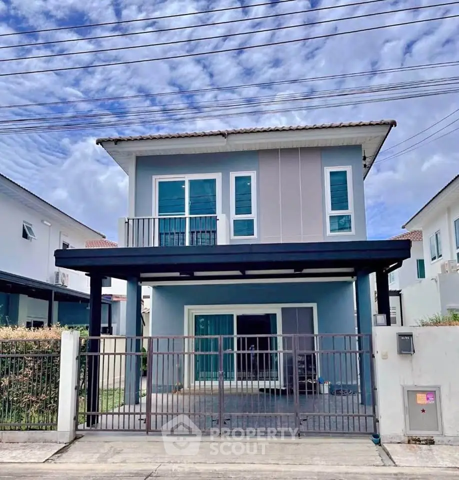 Modern two-story blue house with gated entrance and balcony, perfect for family living.