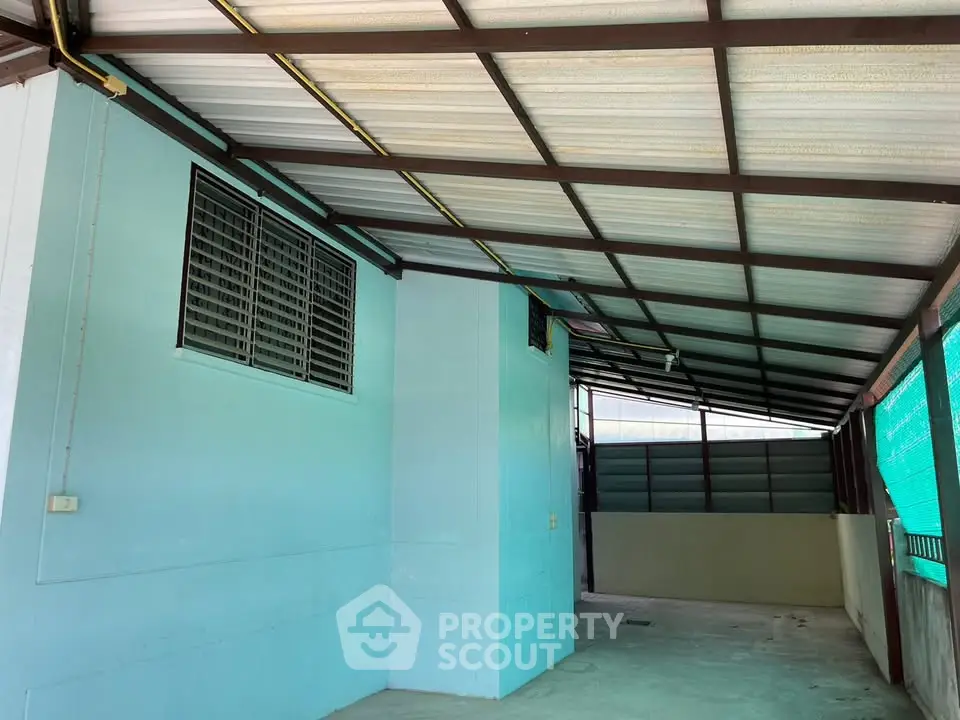 Spacious covered outdoor area with metal roof and blue walls, ideal for parking or storage.