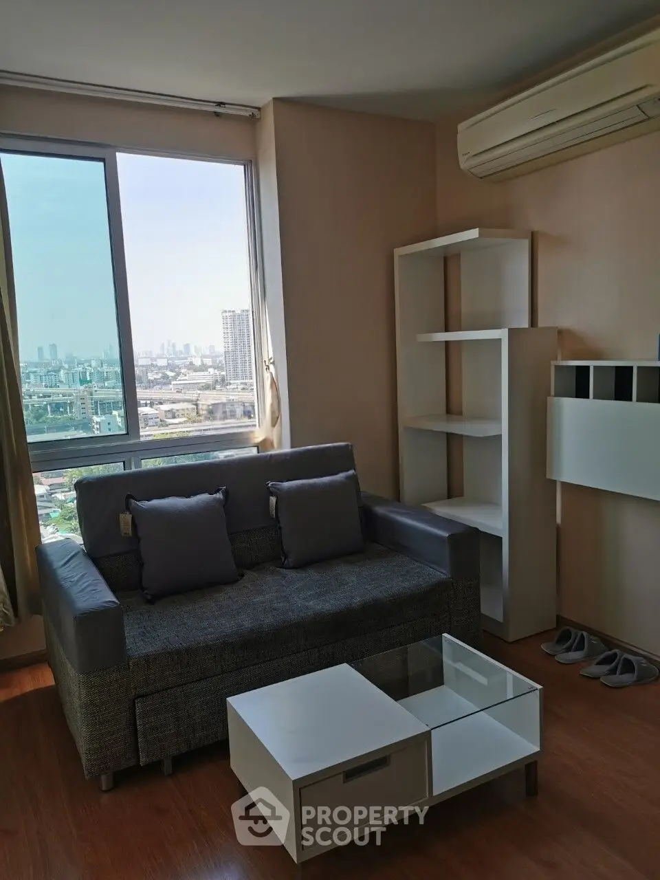 Modern living room with city view, featuring sleek furniture and air conditioning.