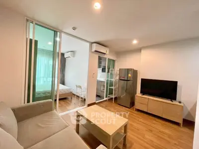Modern open-plan living room with cozy sofa, wooden flooring, and kitchen view in stylish apartment.