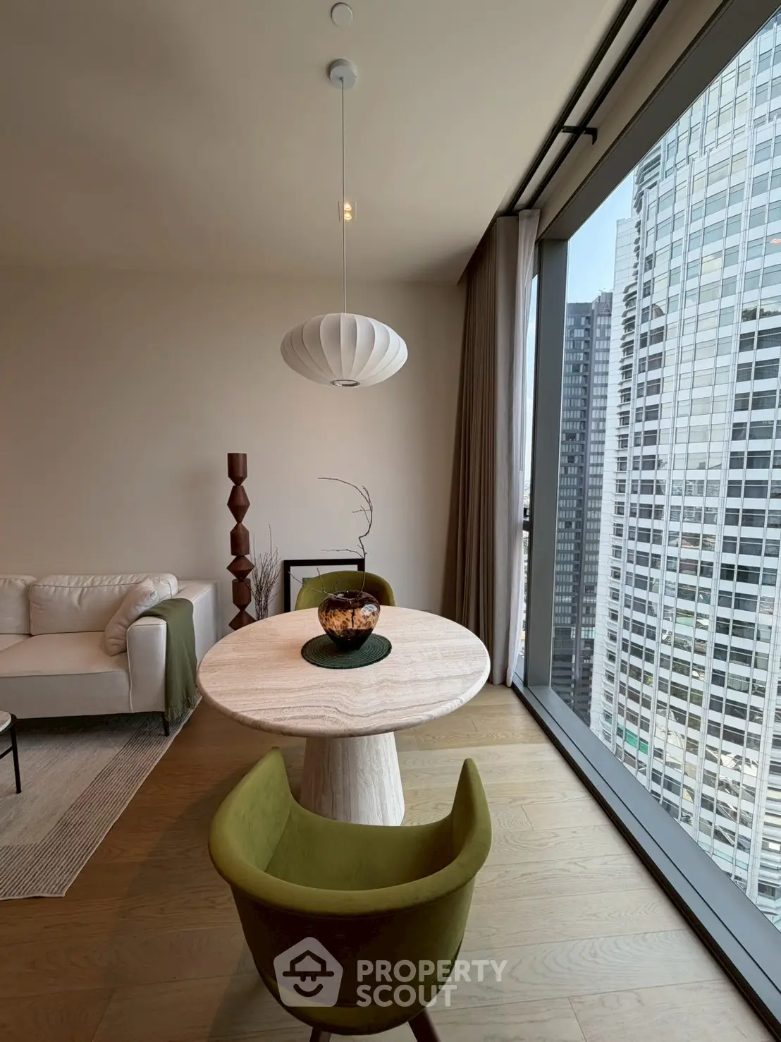 Modern living room with floor-to-ceiling windows and city view, featuring stylish furniture and elegant decor.