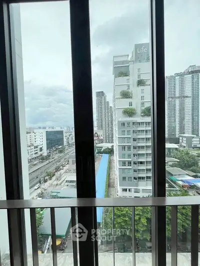 Stunning cityscape view from a modern balcony with high-rise buildings and lush greenery.
