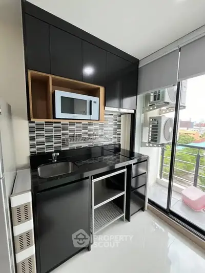 Modern kitchen with sleek black cabinets and balcony view