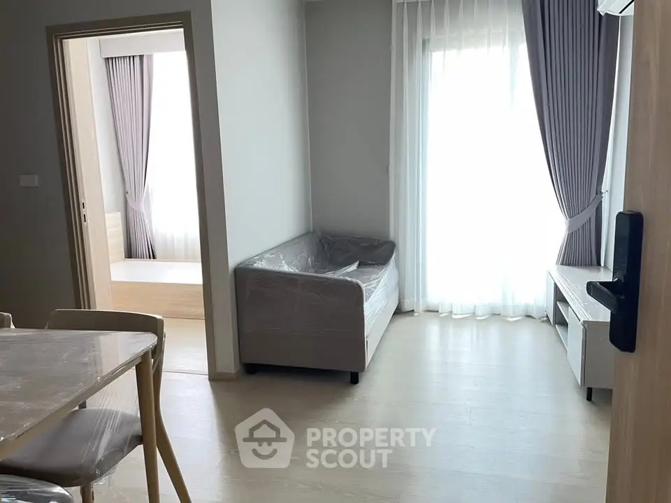 Modern apartment interior with natural light, featuring a cozy living room and dining area.