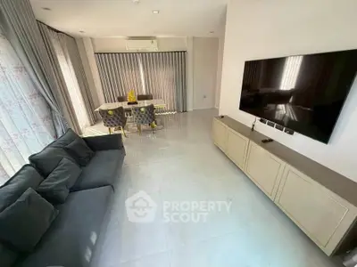 Spacious modern living room with elegant decor and large TV, perfect for relaxation and entertainment.