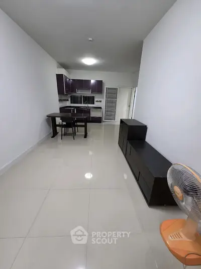 Modern kitchen with sleek cabinets and dining area in open layout apartment.