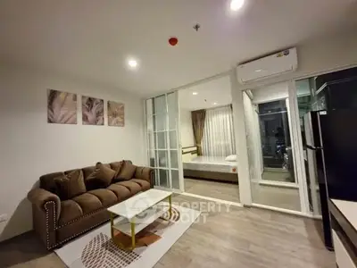 Modern living room with stylish sofa and open layout leading to bedroom, featuring sleek design and cozy ambiance.
