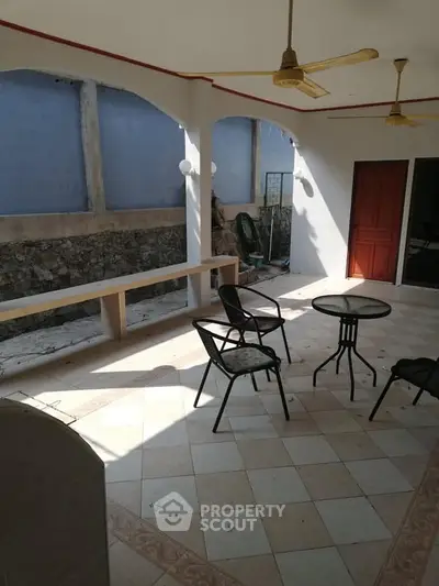 Spacious covered patio with seating area and ceiling fans, perfect for outdoor relaxation.