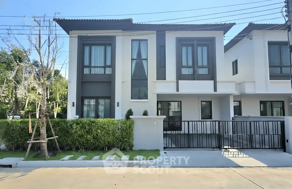 Modern two-story house with sleek design and large windows in a suburban neighborhood.