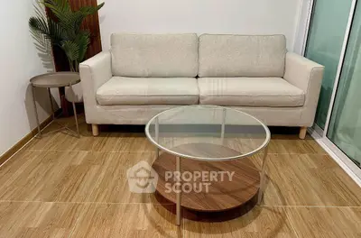 Modern living room with stylish beige sofa and glass coffee table on wooden flooring.