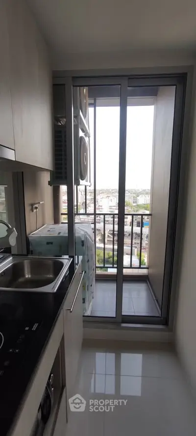 Modern kitchen with sleek design and balcony view in high-rise apartment