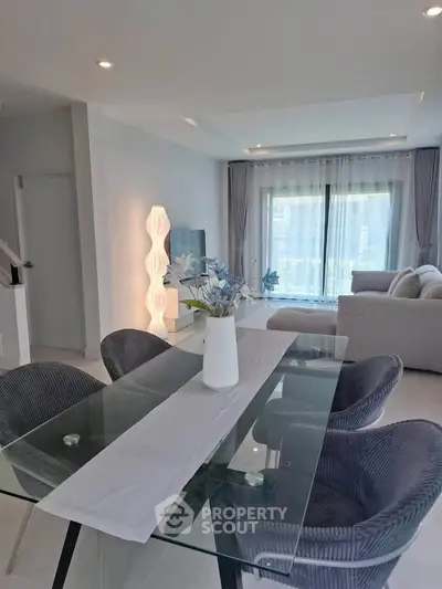 Modern living room with elegant dining area and large windows offering natural light
