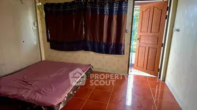 Cozy bedroom with open door leading to a garden view, featuring tiled flooring and simple decor.