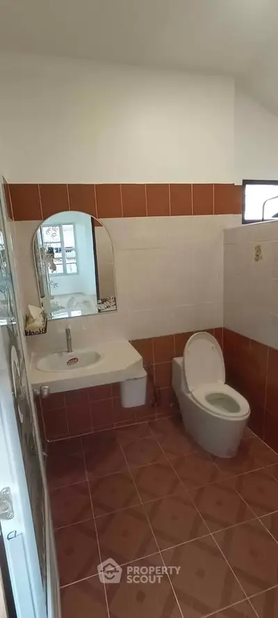 Modern bathroom with tiled walls and floor, featuring a sleek toilet and stylish sink.