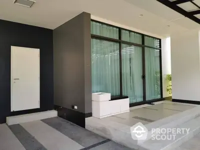 Sleek modern entrance with large glass doors and minimalist design, featuring a striking black wall and elegant steps leading to the doorway.