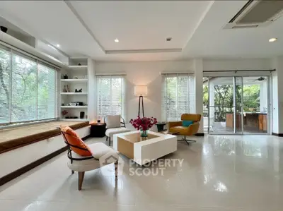 Spacious living room with modern decor and large windows overlooking greenery.