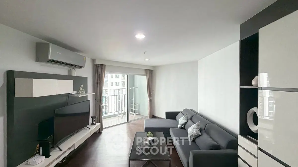 Modern living room with sleek furniture and balcony view in urban apartment.