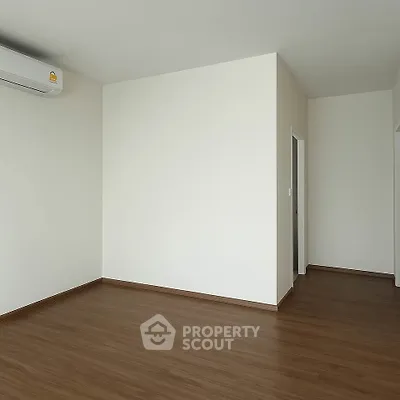 Spacious empty room with wooden flooring and air conditioning unit, perfect for customization.