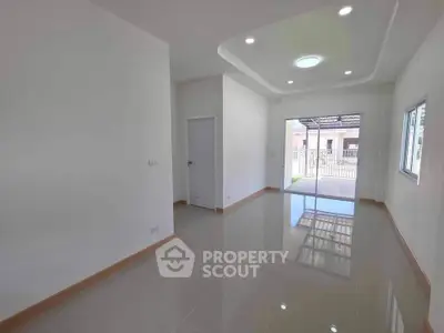 Spacious modern living room with glossy tiled floors and recessed lighting, featuring a view of the entrance.