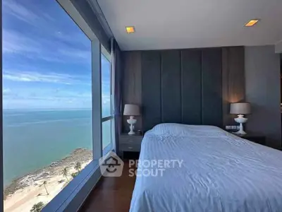 Luxurious bedroom with stunning ocean view through large windows, featuring elegant decor and cozy ambiance.