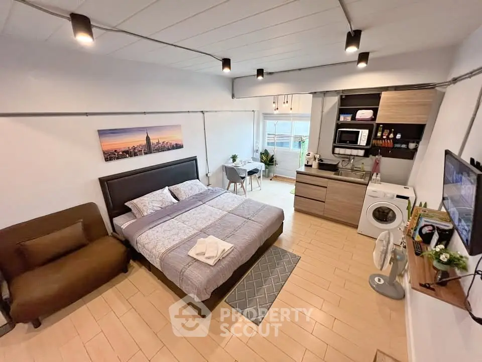 Modern studio apartment with cozy bedroom and compact kitchen area.