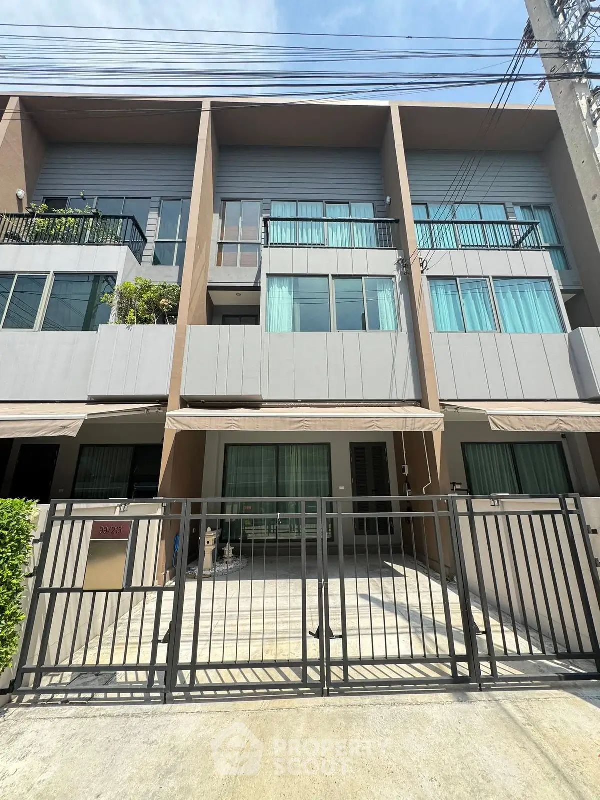 Modern townhouse exterior with gated entrance and large windows in a sunny neighborhood.