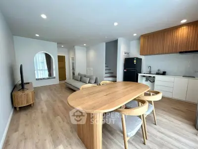 Modern open-plan living room and kitchen with wooden furniture and sleek design.