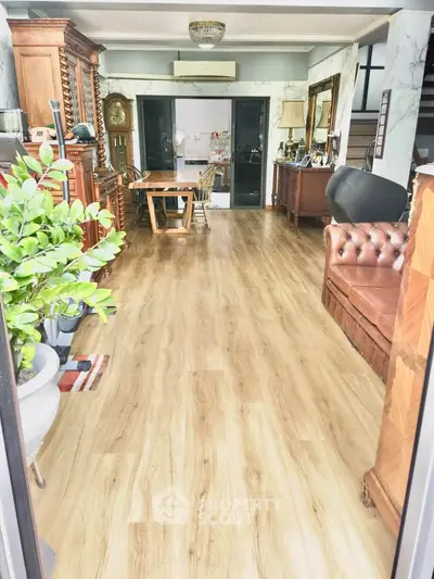 Spacious living room with elegant wooden flooring and classic furniture, perfect for family gatherings.