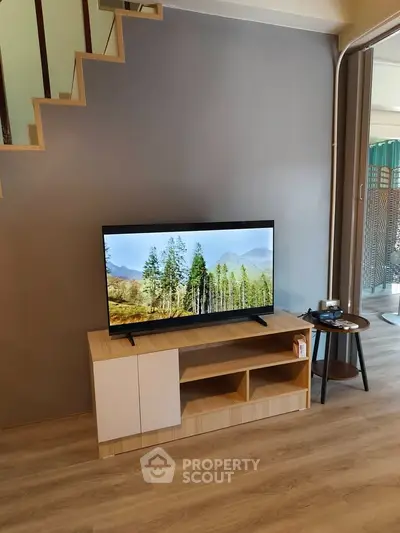 Modern living room with stylish TV stand and flat-screen TV under staircase