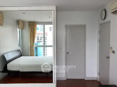 Modern bedroom with mirrored closet and city view, featuring sleek design and natural light.