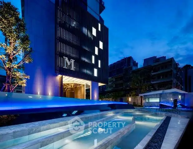 Luxurious modern building with illuminated pool at dusk, showcasing elegant architecture.