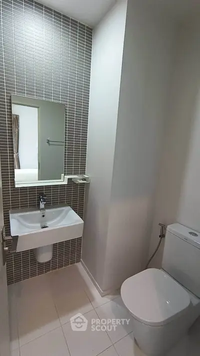 Modern bathroom with sleek sink and toilet, featuring stylish tile wall design.