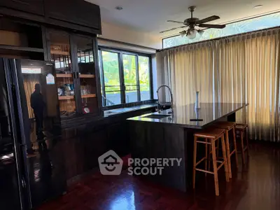Spacious kitchen with dark wood cabinets and large island, featuring modern appliances and ample natural light.