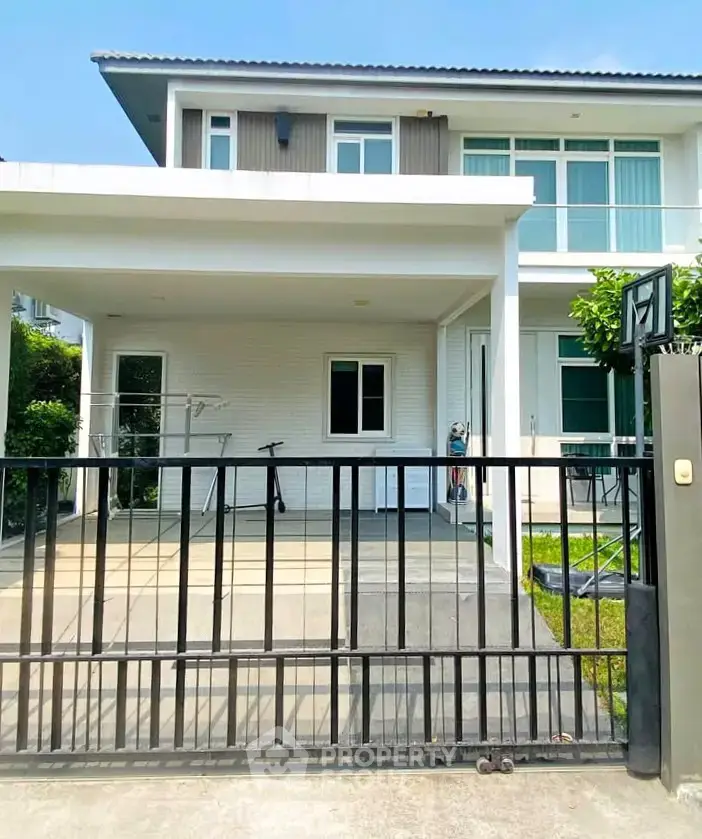 Modern two-story house with gated driveway and lush greenery, perfect for family living.