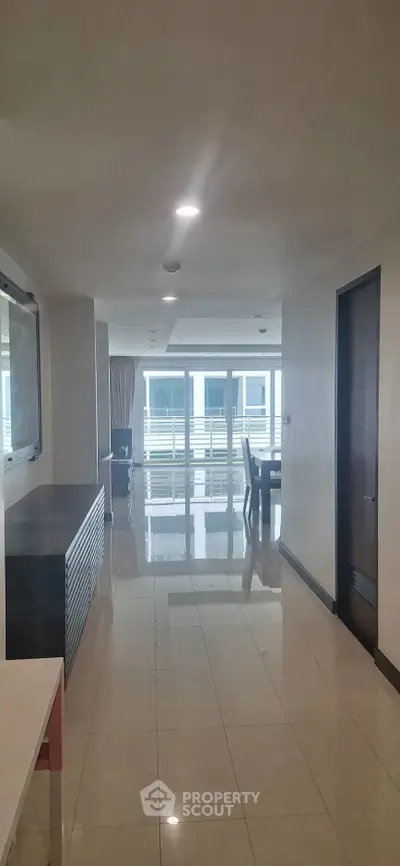 Spacious modern apartment hallway leading to a bright living area with large windows.